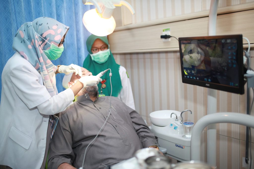 Dokter gigi memeriksa pasien di kursi perawatan