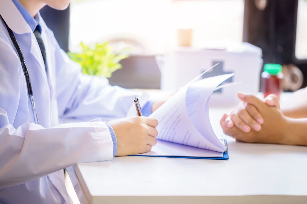 Dokter mencatat hasil konsultasi dengan pasien